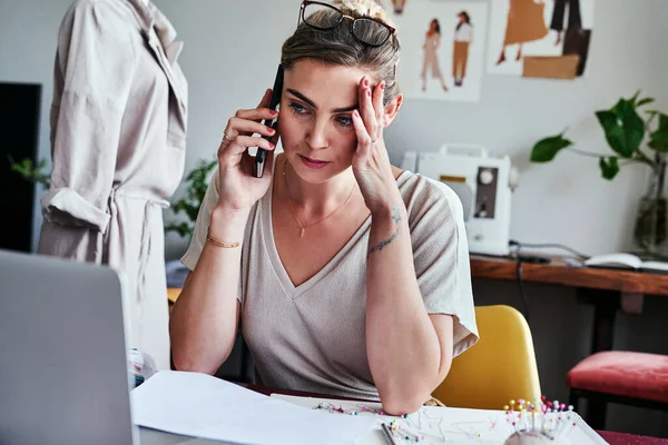 No podré terminar a tiempo. Fotografía de una joven diseñadora que se ve estresada mientras habla por su teléfono celular. — Foto de Stock