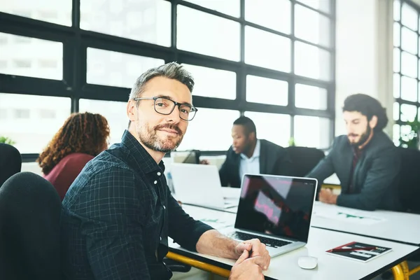 J'ai la meilleure équipe du métier. Portrait recadré d'un homme d'affaires mature travaillant à un bureau avec ses collègues au bureau. — Photo