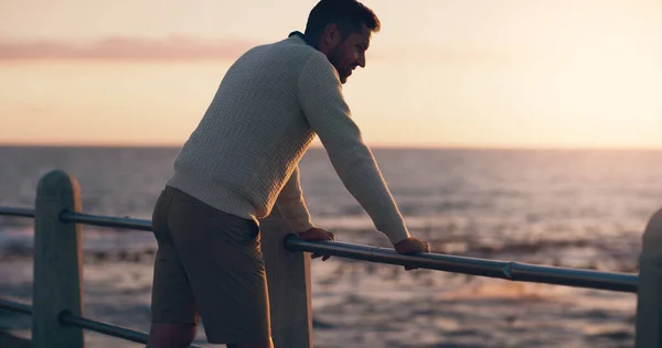 A terminar um longo dia na praia. Rearview tiro de um homem assistindo o pôr do sol na praia. — Fotografia de Stock