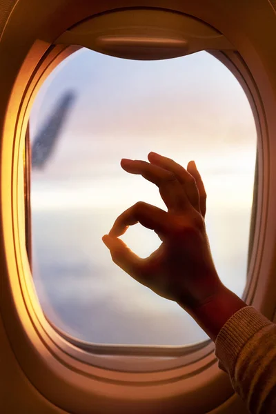 Deze vlucht gaat prima. Schot van een passagier die een goed teken maakt terwijl hij door het raam van een vliegtuig kijkt.. — Stockfoto