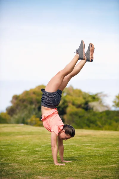 Door fitness is ze sterk en flexibel geworden. Shot van een jonge aantrekkelijke vrouw doet een handstand buiten. — Stockfoto