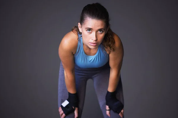 Mantenha-se forte mental e fisicamente. Retrato de uma jovem esportiva recuperando o fôlego contra um fundo cinza. — Fotografia de Stock