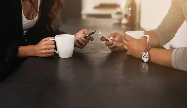 O que é melhor do que café e wi-fi. Tiro recortado de um jovem casal usando seus telefones celulares e tomando café em casa. — Fotografia de Stock