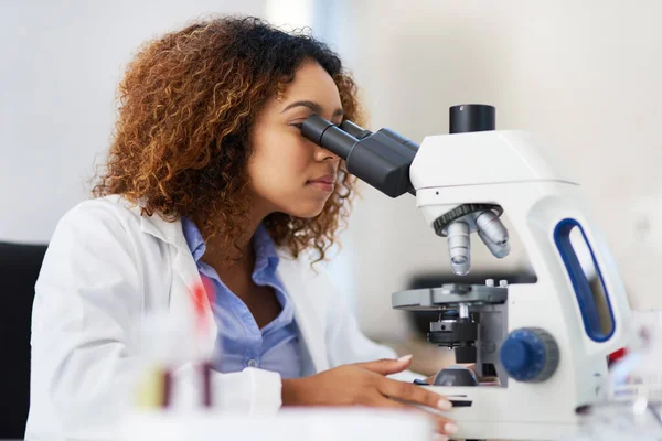 Analyse van microscopische gegevens. Gehakte opname van een jonge vrouwelijke wetenschapper die in een microscoop kijkt. — Stockfoto