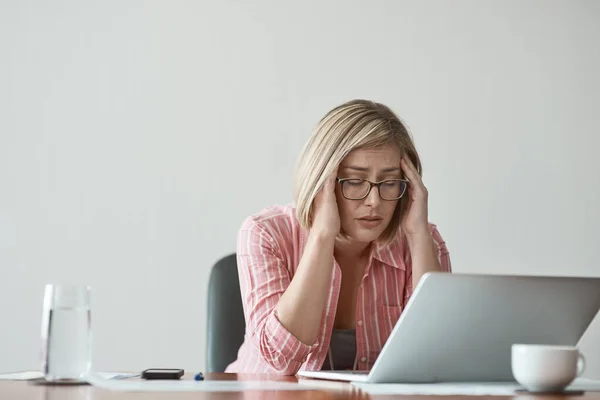 Te terminy przyprawiają mnie o ból głowy. Studyjne ujęcie bizneswoman wyglądającej na zestresowaną podczas pracy na laptopie na szarym tle. — Zdjęcie stockowe