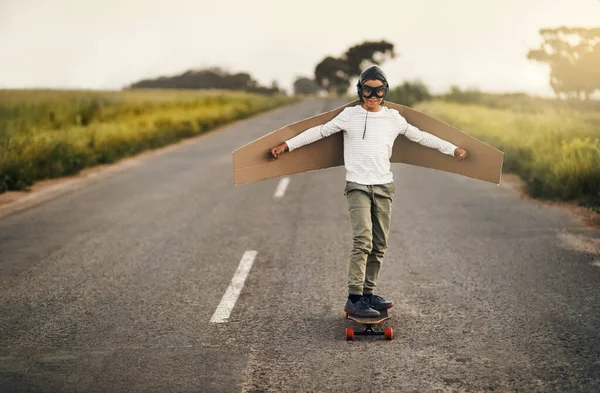 Этот скейтер умеет парить. Застрелен мальчиком, который притворяется, что летает с картонными крыльями во время езды на скейтборде.. — стоковое фото
