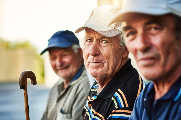 De wijze mannen van de stad. Portret van een groep vrolijke oudere mannen die bij elkaar zitten terwijl ze in de camera buiten kijken. — Stockfoto