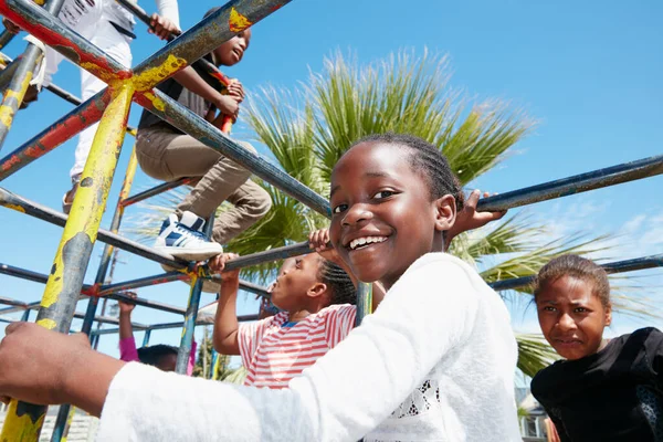 The world is their playground. Portrait of a happy little girl playing on a jungle gym. — Stock Photo, Image