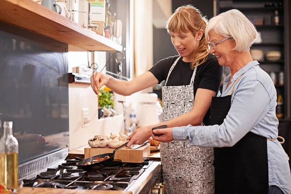 Mestarikokilta oppimista. Laukaus vanhempi nainen ja nuorempi nainen ruoanlaitto yhdessä. — kuvapankkivalokuva