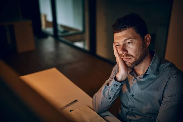 Posso ir para casa, por favor? Tiro de um jovem empresário que parece entediado enquanto trabalhava até tarde em um escritório. — Fotografia de Stock