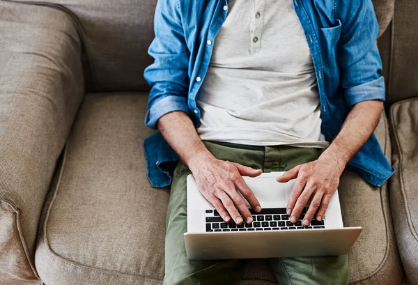 Online, de hele tijd. Hoge hoek schot van een onidentificeerbare vrijgezel met behulp van zijn laptop terwijl ontspannen op de bank. — Stockfoto