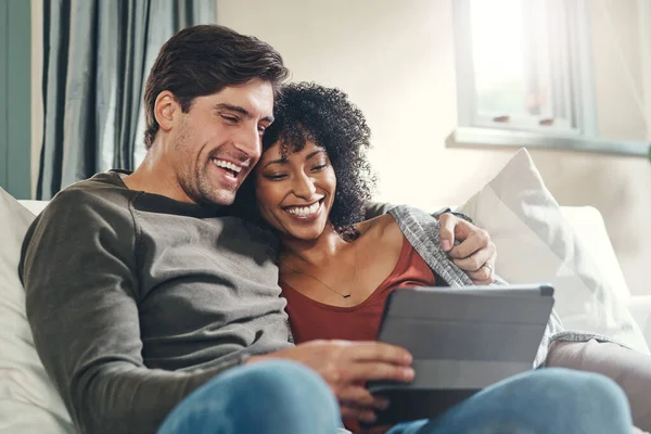 Es passiert immer etwas Interessantes im Internet. Aufnahme eines liebevollen jungen Paares, das gemeinsam ein digitales Tablet benutzt, während es einige Zeit zu Hause zusammen verbringt. — Stockfoto