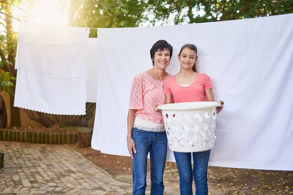 彼女は家事をお母さんを助けている。外で一緒に洗濯物を干している母娘の肖像画. — ストック写真