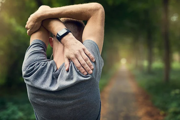 O custo da aptidão. Rearview tiro de um homem aquecendo antes de uma corrida. — Fotografia de Stock