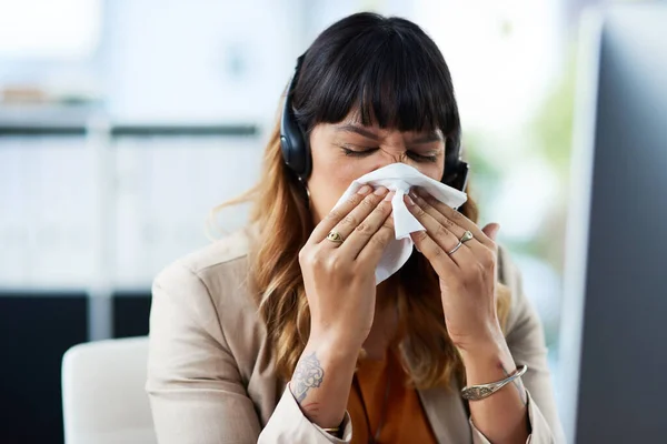 Chyba się przeziębiłam. Ujęcie atrakcyjnej młodej bizneswoman cierpiącej na przeziębienie i wydmuchiwanie nosa podczas pobytu w biurze. — Zdjęcie stockowe