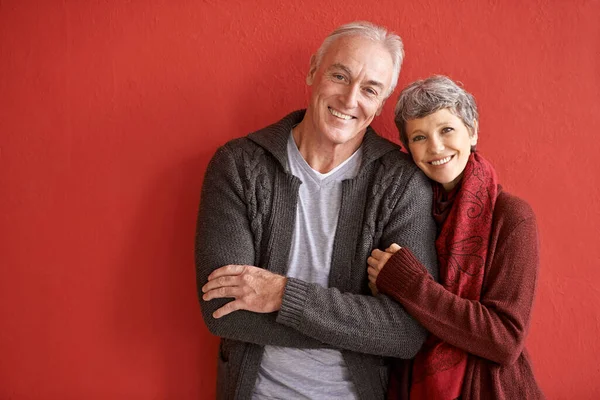 Liebe ist Langlebigkeit. Aufnahme eines liebevollen Seniorenpaares, das vor rotem Hintergrund steht. — Stockfoto