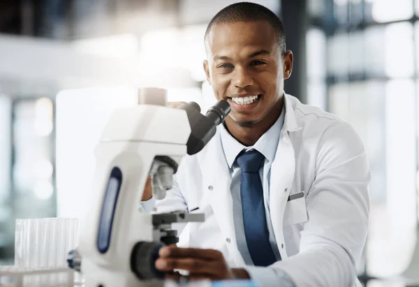 Eine Entdeckung nach der anderen verändert die Welt. Ausgeschnittenes Porträt eines hübschen jungen Wissenschaftlers unter dem Mikroskop, während er in seinem Labor forscht. — Stockfoto