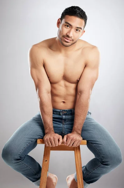 Désir assez fort pour voir. Plan studio d'un beau jeune homme montrant son corps musclé assis sur une chaise sur un fond gris. — Photo