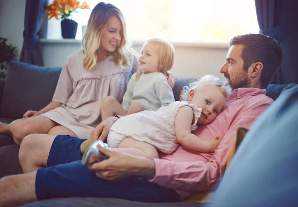 Arranja tempo para aqueles que amas. Tiro de uma adorável jovem família de quatro relaxantes juntos no sofá em casa. — Fotografia de Stock