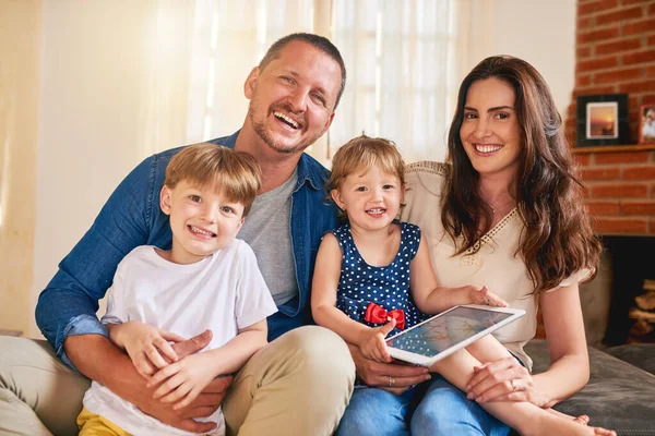 Το ευτυχισμένο σπίτι φτιάχνεται με την αγάπη μιας οικογένειας. Πορτρέτο μιας χαρούμενης νεαρής οικογένειας τεσσάρων ατόμων που χαλαρώνουν μαζί στον καναπέ στο σπίτι. — Φωτογραφία Αρχείου
