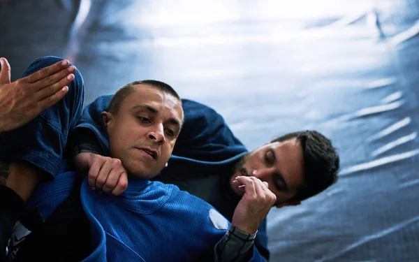 Tap out. Cropped shot of two young male athletes sparring on the floor of their dojo. — Stock Photo, Image