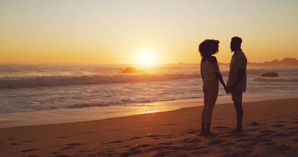 未来は私のそばであなたと一緒に明るく見える。夕日のビーチに立つ愛情のある若いカップルの完全な長さのショット. — ストック写真