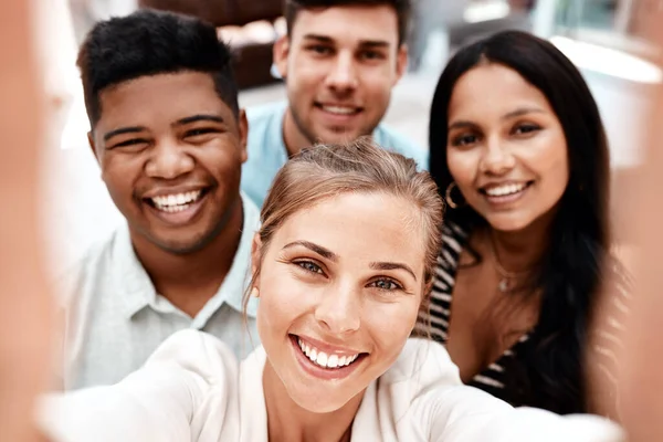 Za tymi uśmiechami kryje się sukces. Przycięty portret grupy młodych kolegów z pracy, robiących sobie selfie w biurze. — Zdjęcie stockowe