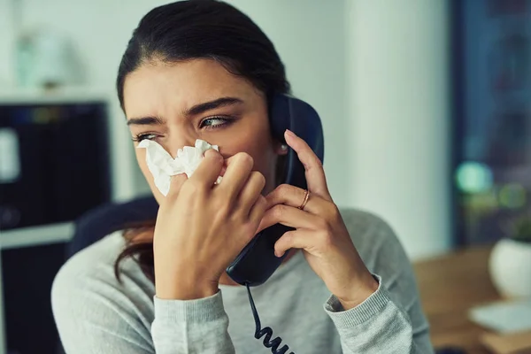 E 'ora di chiamare il dottore. Girato di una giovane donna d'affari che si soffia il naso mentre parla al telefono in un ufficio. — Foto Stock