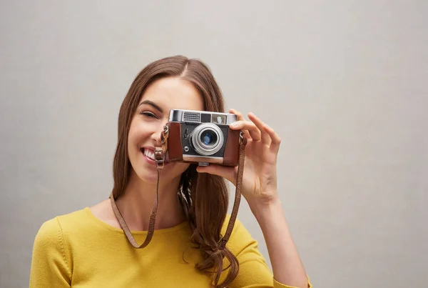 So fotogen. Studioporträt einer attraktiven jungen Fotografin, die mit ihrer Kamera vor grauem Hintergrund posiert. — Stockfoto