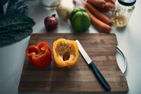 Ingredientes essenciais. Tiro de ângulo alto de pimentas cortadas em uma tábua de redução rodeiam por várias verduras em um balcão de cozinha. — Fotografia de Stock