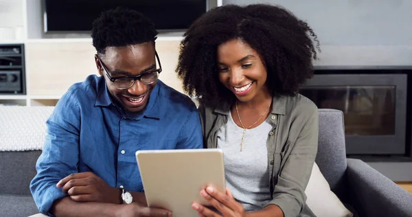 Kijk wat er online trending is. Shot van een vrolijk jong stel met behulp van een digitale tablet samen thuis. — Stockfoto