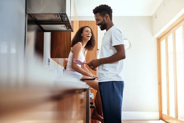 Não posso esperar pelo pequeno-almoço. Cortado tiro de um jovem bonito cozinhar na cozinha, enquanto sua esposa assiste em. — Fotografia de Stock