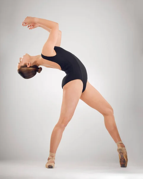 Свобода передвижения. Полнометражный снимок привлекательной молодой балерины в студии на сером фоне. — стоковое фото