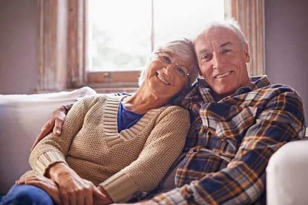 Mutlulukla zamana karşı kayıtsız. Evlerindeki oturma odalarında oturan mutlu yaşlı bir çiftin portresi.. — Stok fotoğraf