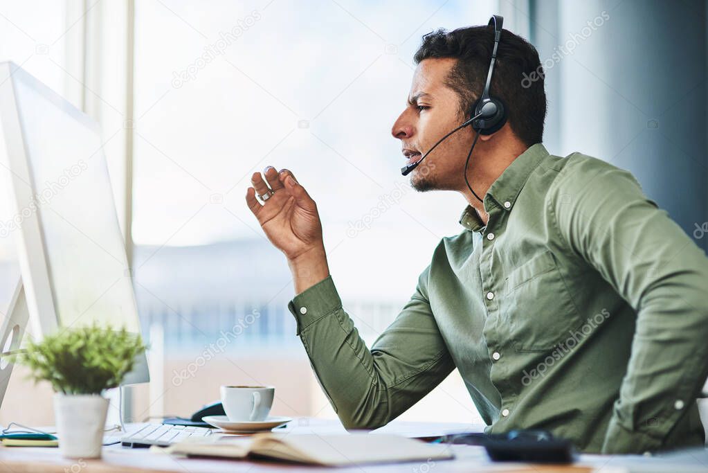 He gives the best financial advice. Shot of a confident young businessman talking through a headset while being seated at his desk in the office.