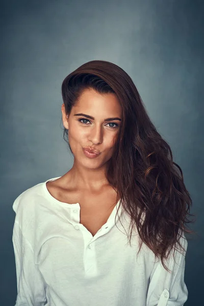 Kop op. Portret van een mooie jonge vrouw trekken een grappig gezicht tegen een grijze achtergrond in studio. — Stockfoto