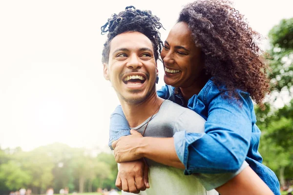 Esteja com alguém que pode fazer qualquer dia um bom. Tiro de um jovem casal feliz desfrutando de um passeio de piggyback ao ar livre. — Fotografia de Stock