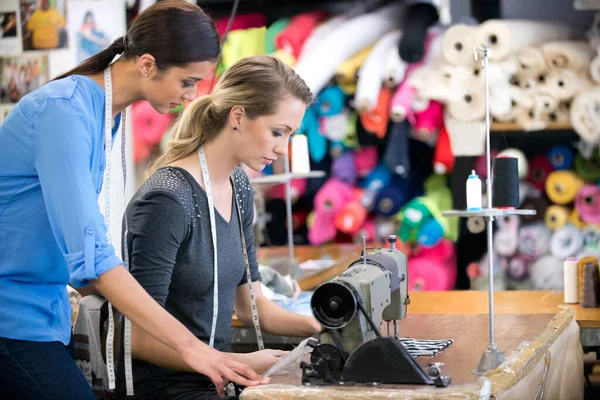 Všechno musí být perfektní. Dvě ženy pracující na oděvu na pracovním stole v jejich textilním obchodě. — Stock fotografie