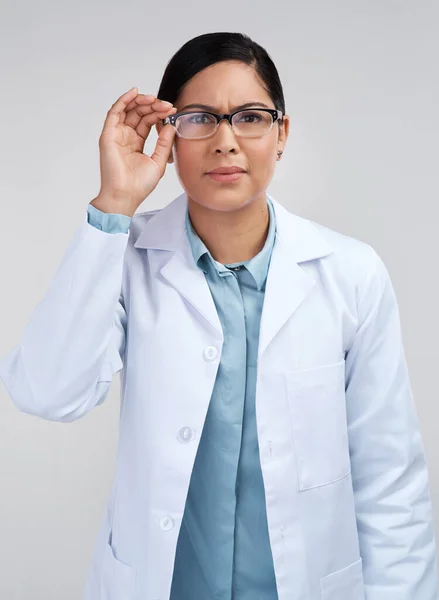 彼女はいつも何かを分析する。灰色の背景を持つスタジオで眼鏡をかけて魅力的な若い女性科学者の作物の肖像画. — ストック写真
