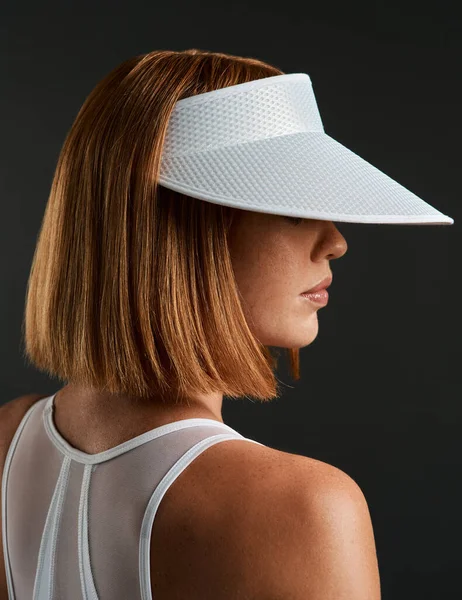 I advise you to wear your visor. Cropped shot of a sporty young woman wearing a sun visor against a dark background. — Stock Photo, Image