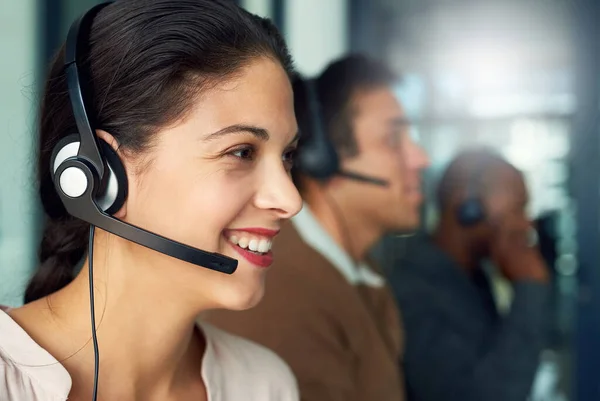 Daar helpt u uw problemen snel en efficiënt op te lossen. Opname van een call center agent in een kantoor met haar collega 's op de achtergrond. — Stockfoto
