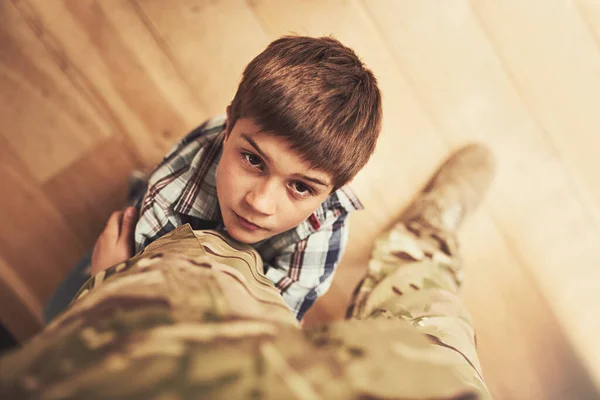 ¿De verdad tienes que irte? Un disparo de un joven que se aferra a la pierna de su padre para impedirle ir al ejército. — Foto de Stock