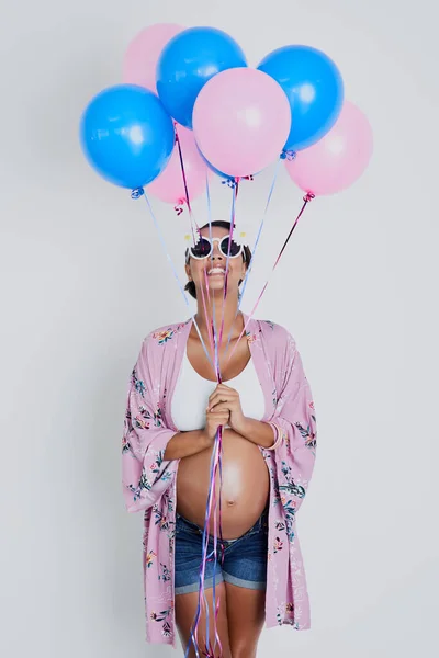 Ragazza, ragazzo rosa o blu cosa sarà il mio bambino. Studio girato di una bella giovane donna incinta che tiene palloncini blu e rosa su uno sfondo grigio. — Foto Stock