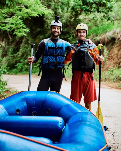 Lo facciamo da quando eravamo bambini. Ritratto di due giovani allegri che indossano un equipaggiamento protettivo mentre ognuno tiene una pagaia per andare a fare rafting sul fiume. — Foto Stock