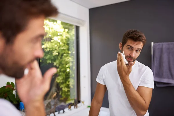 Nejdřív krém na holení, abych si chránil kůži. Vystřižený záběr pohledného muže, který si doma nanáší krém na holení na obličej v koupelně. — Stock fotografie