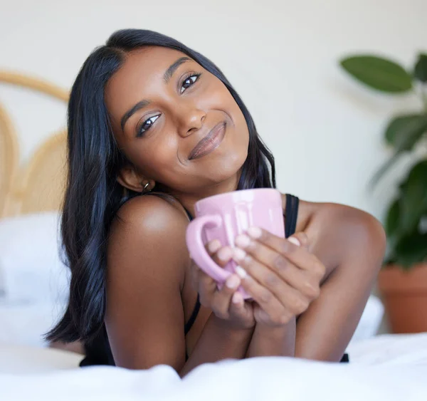 Una taza de café fresco por la mañana. Retrato de larga duración de una atractiva joven disfrutando de una taza de café mientras está acostada en una cama. — Foto de Stock