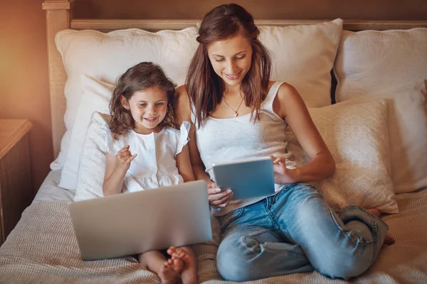 Cieszą się razem spędzonym razem czasem w sieci. Zdjęcie dziewczynki korzystającej z laptopa i jej matki korzystającej z tabletu cyfrowego w domu. — Zdjęcie stockowe
