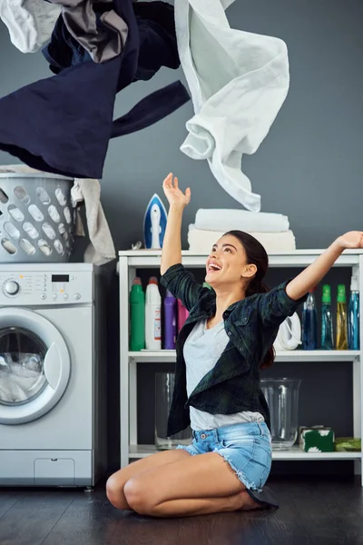 Its laundry day. Full length shot of an attractive young woman throwing her washing in the air while doing laundry at home. — Stock Photo, Image