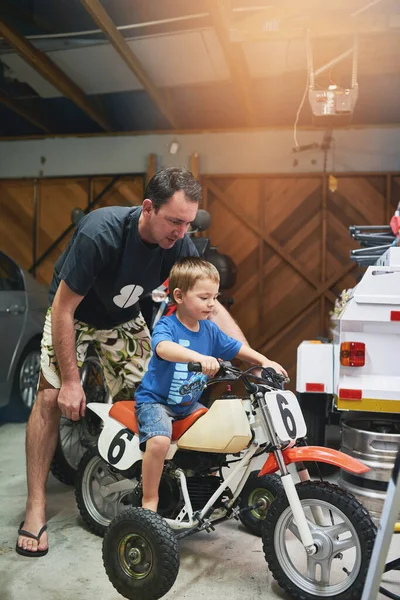 Il est temps de tester le vélo. Prise de vue d'un père et d'un fils réparant un vélo dans un garage. — Photo