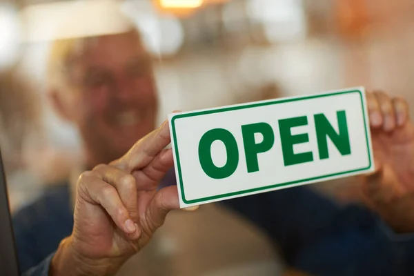 O seu funcionário - foram abertos para o negócio. Tiro de um empresário sênior feliz segurando um sinal aberto na porta de seu café. — Fotografia de Stock